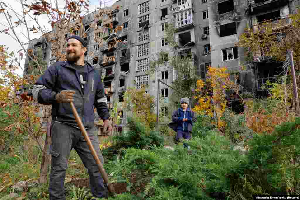 Мариупольец и его маленький племянник работают во дворе поврежденного дома 29 октября. Мариуполь был захвачен российскими войсками в мае после нескольких месяцев боев, в результате которых около 90 процентов городских зданий были повреждены или разрушены. Тысячи людей погибли в так называемой осаде Мариуполя.