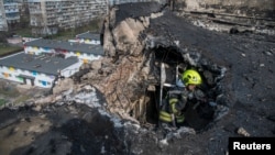 A Ukrainian firefighter works at a site an apartment building hit by a Russian drone strike, in Kyiv on March 23.